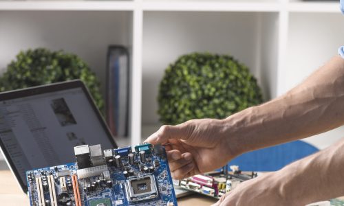close up male technician holding modern computer motherboard from table
